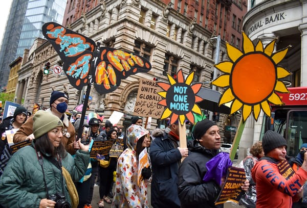 A crowd of marchers holding colorful signs celebrate International Workers Day, or May Day, on May 1, 2023, in Downtown Pittsburgh.